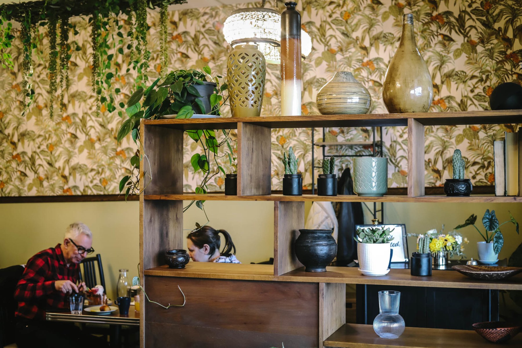 Plant-filled dining room with botanical wallpaper.