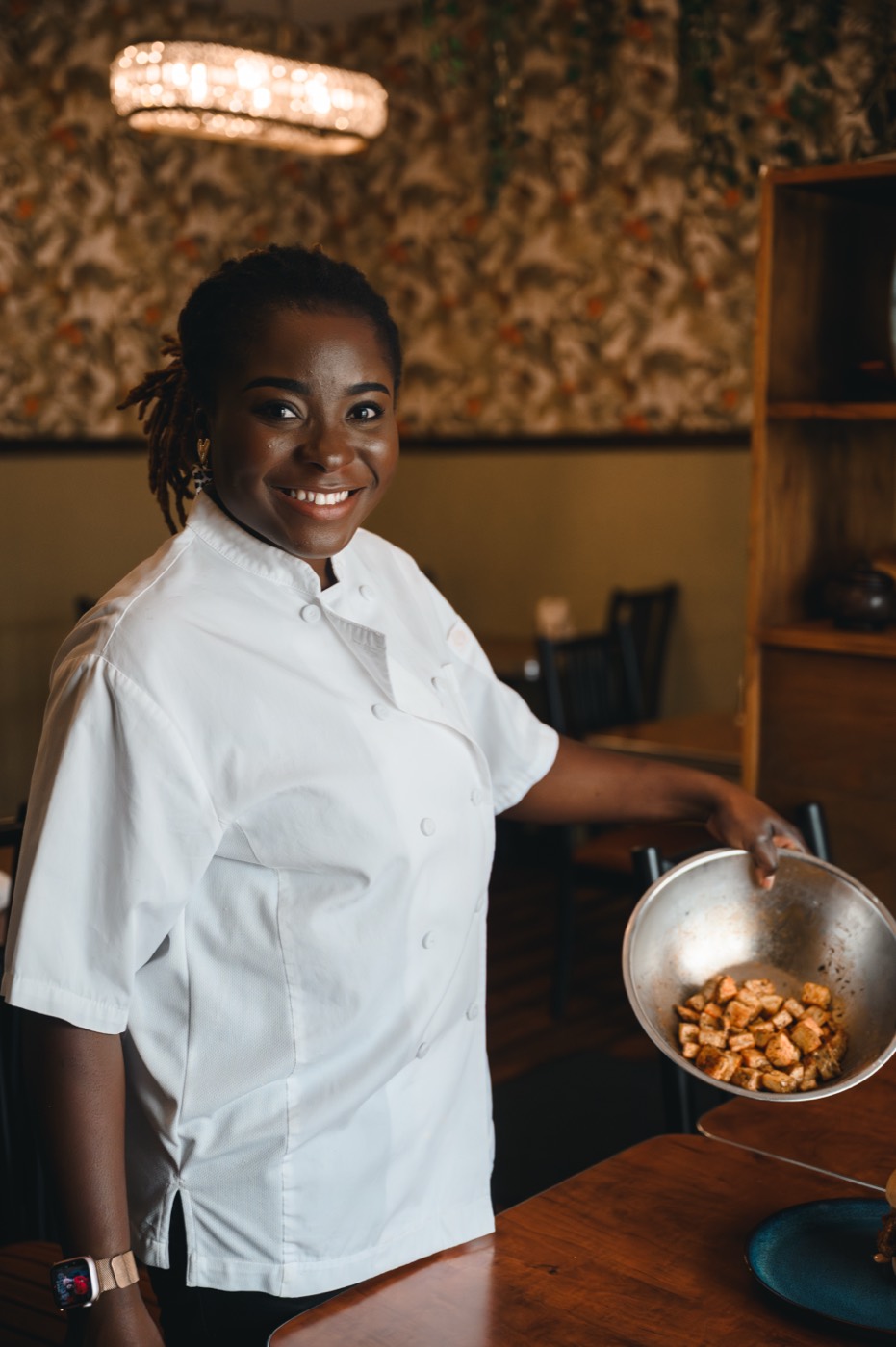 The chef-owner serving puff puff, mid-laugh.